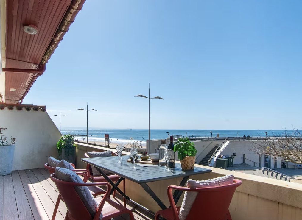 Terrasse d'appartement face à l'océan, table dressée et fauteuils